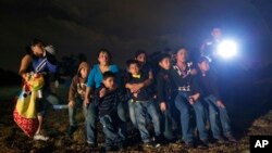 FILE - Immigrants from Honduras and El Salvador who crossed the Mexico-U.S. border illegally are stopped in Granjeno, Texas, June 25, 2014.