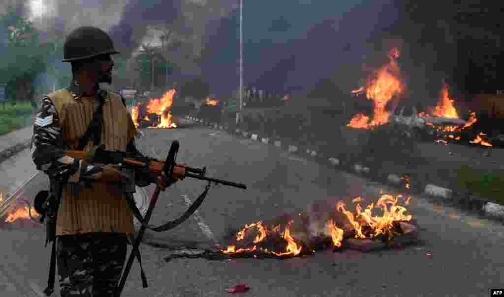 Indian security personnel looks at burning vehicles set alight by rioting followers of a religious leader convicted of rape in Panchkula.