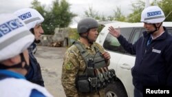 Members of the Organization for Security and Cooperation in Europe (OSCE) speak with a Ukrainian serviceman as they visit the town of Zolote in Luhansk region, Sept. 26, 2016.