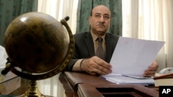 FILE - Hesham Genena, the head of Egypt's oversight body, holds documents at his office in Cairo, April 16, 2014.