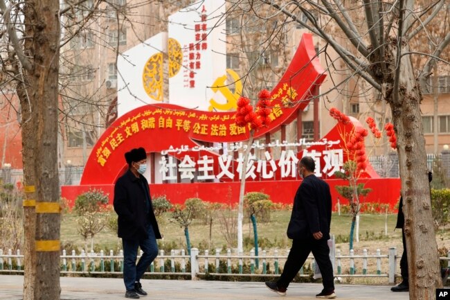 FILE - Residents walk past government propaganda, some of which reads,