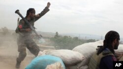 FILE - An Afghan National Army soldier, left, shouts against the Taliban, after firing a rocket towards Taliban positions, on the outskirts of Kunduz, northern Afghanistan, Apr. 16, 2016. 