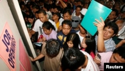 FILE - Filipino job seekers look at job openings posted on a board inside a Philippine Overseas Employment Agency (POEA) in Manila.