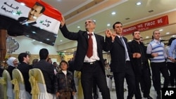 Syrian Kurds carry a Syrian flag bearing a picture of President Bashar Assad and Arabic writing that reads: "God protects Syria's Assad" as they celebrate the Nowruz spring festival with a traditional dance in Damascus, March 20, 2011