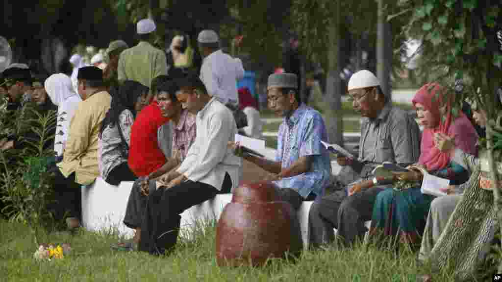 Des Acehnais en train de lire le Coran devant une fosse commune au cours du 10e anniversaire du tsunami en Siron, Aceh Besar, l&#39;Indonésie, le vendredi 26 décembre 2014.