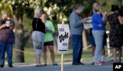 FILE - Voters stand in line to vote at an early voting polling site in San Antonio, Oct. 20, 2014.