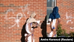 Mahawa dan Xiomara Kouyate, berasal dari Guinea, bermain di luar Guiding Light Islamic Center selama pertemuan Idul Fitri di Louisville, Kentucky, AS, 13 Mei 2021. (Foto: REUTERS/Amira Karaoud)