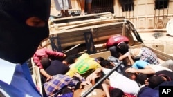 An Islamic fighter guards alleged Iraqi soldiers lying in a truck bed in this photo posted on a militant website June 14, 2014.