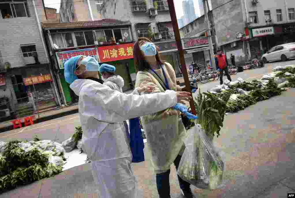 A resident, not pictured, uses a belt to have vegetables raised up in Wuhan, in China&#39;s central Hubei province, during the coronavirus pandemic. 