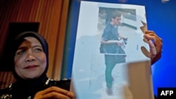 Una oficial de la policía malaya, muestra una foto del iraní Pouria Nour Mohammad Mehrdad, uno de los dos hombres que abordo el avión desaparecido usando pasaporte falso.