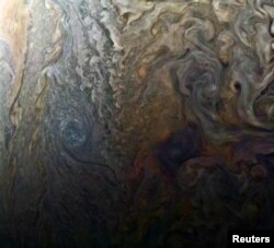 FILE - NASA's enhanced-color image of a mysterious dark spot on Jupiter shows a Jovian "galaxy" of swirling storms in this image captured by NASA's Juno spacecraft, Feb. 2, 2017, at an altitude of 9,000 miles (14,500 kilometers) above Jupiter's cloud tops.