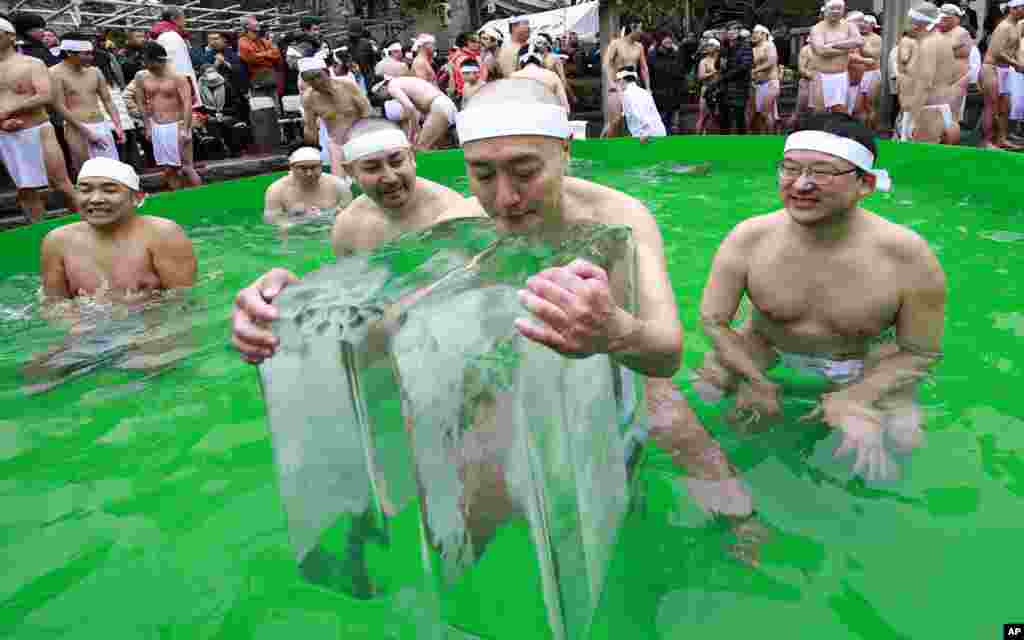 Japanese bathers pray for the healthy New Year while dipping in a cold water tub with blocks of ice at a park by Teppozu Inari Shinto Shrine during a winter ritual in Tokyo.
