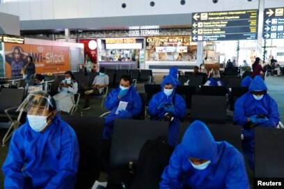 Pelancong yang mengenakan pakaian pelindung terlihat di bandara Internasional Soekarno Hatta, karena negara itu melarang kedatangan pelancong yang telah berada di delapan negara Afrika untuk mengekang penyebaran omicron baru. (Foto: Reuters)