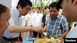 Philippine President Rodrigo Duterte and Japan's Prime Minister Shinzo Abe (left) try durian fruit after attending various events at the Waterfront Hotel in Davao City, southern Philippines, Jan. 13, 2017.