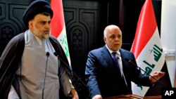 FILE - In this photo provided by the Iraqi government, Iraqi Prime Minister Haider al-Abadi, right, and Shiite cleric Muqtada al-Sadr hold a press conference in Baghdad, Iraq, May 20, 2018. 