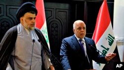 FILE - In this photo provided by the Iraqi government, Iraqi Prime Minister Haider al-Abadi, right, and Shiite cleric Muqtada al-Sadr hold a press conference in Baghdad, May 20, 2018. 