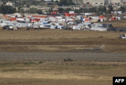 A picture taken on July 2, 2018 from the Israeli-annexed Syrian Golan Heights shows an Israeli army vehicle patrolling the border fence opposite a Syrian camp for the displaced near the village of Al-Rafeed in the southern Syrian province of Daraa.