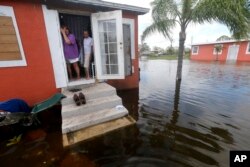 Quintana and Liz Perez look at the flooding outside their home in the aftermath of Hurricane Irma, Sept. 11, 2017, in Immokalee, Fla.
