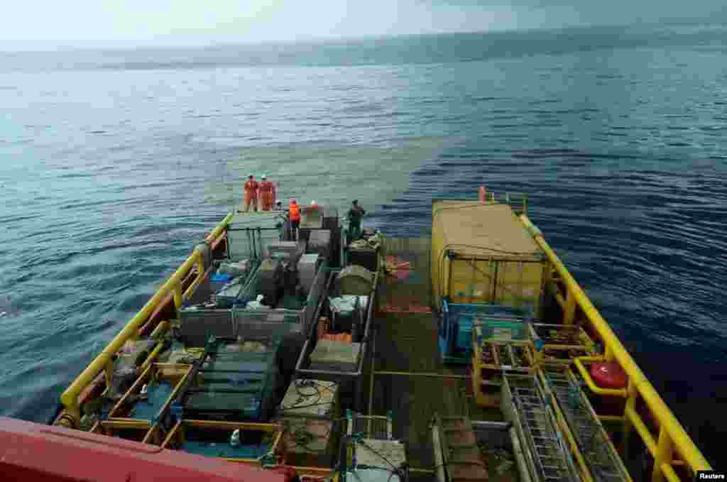 Pegawai PT. Pertamina bersiaga di atas kapal Prabu milik PT. Pertamina seraya mengamati apa yang diduga sebagai serpihan dari pesawat Lion Air nomor penerbangan JT 610, di lepas pantai Karawang, Jawa Barat, 29 Oktober 2018.