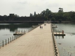 A small group of tourists walk on a bridge connecting to the Angkor Wat temple in Siem Reap province, Cambodia, March 18, 2020. (Hul Reaksmey/VOA Khmer)