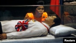 FILE - Former Philippine first lady Imelda Marcos kisses the glass coffin of her husband, late dictator Ferdinand Marcos, who remains unburied since his death in 1989, in the town of Batac, Ilocos Norte province, north of Manila, March 26, 2010. 