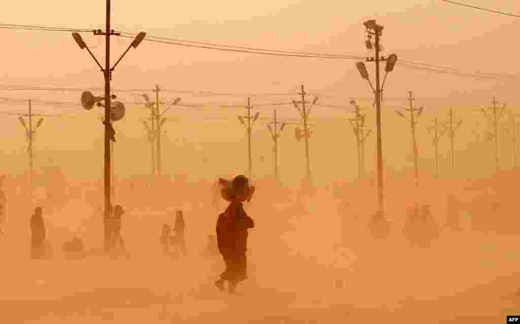 Indian Hindu devotees walk through a dust storm at the Sangam after taking a holy dip at the confluence of the rivers Ganges, Yamuna and mythical Saraswati during the Maha Kumbh festival in Allahabad. 