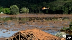 Rescue workers in a helicopter search a flooded area after a dam collapsed in Brumadinho, Brazil, Jan. 27, 2019. 