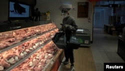 一名戴著口罩的互聯網供貨商在北京亦莊一家肉店為網上訂戶購買豬肉。（2020年2月8日） 