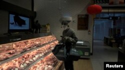 一名戴著口罩的互聯網供貨商在北京亦莊一家肉店為網上訂戶購買豬肉。（2020年2月8日）