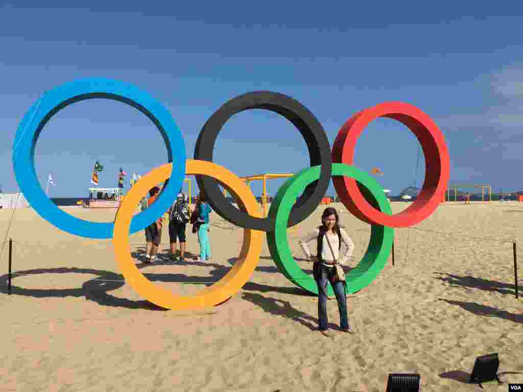 دختر جوانی که با علامت المپیک عکس می گیرد. بسیاری دیگر نیز در صف عکاسی هستند.