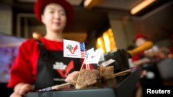FILE - A hostess holds a tray of sliced American beef at an event to celebrate the re-introduction of American beef imports to China, in Beijing, China.