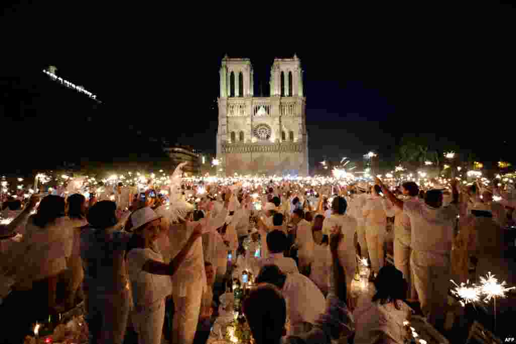 June 16: People celebrate with sparklers as they attend the White Dinner event in front of the Notre Dame Cathedral in Paris. Participants attend the dinner, which takes place at a different place in Paris every year, are required to be dressed in white, 