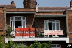 FILE - Banners of opposing views on Britain's Brexit referendum on continued EU membership are displayed on the balconies of two neighboring apartments in the Gospel Oak area of north London, Briatin, May 27, 2016.