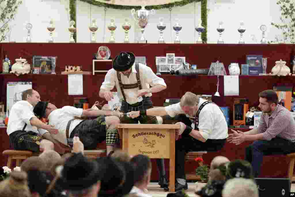 A man dressed in traditional clothes tries to pull his opponent over the table at the 40th Alpine Country Championships in Fingerhakeln in Woernsmuehl, , Germany.