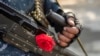 Seorang anggota Taliban dengan bunga mawar di senapan mesinnya mengamankan sebuah area di Kabul, Afghanistan, 4 Desember 2021. (Foto: AP)