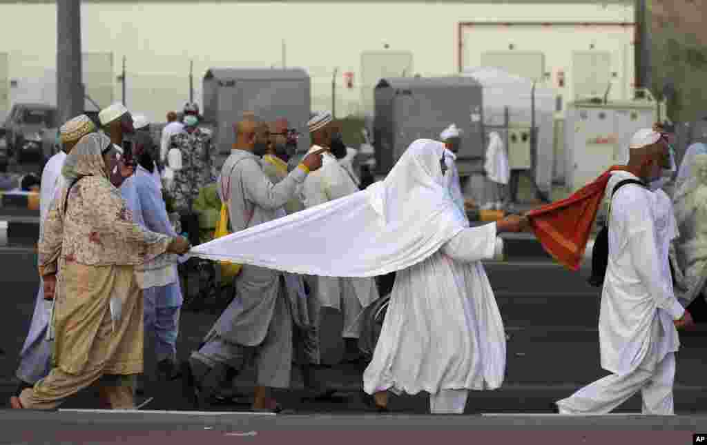 Pakistani Muslim pilgrims hold to each other to avoid being separated as they walk to cast stones at a pillar in the symbolic stoning of the devil, the last rite of the annual hajj, on the second day of Eid al-Adha, in Mina near the holy city of Mecca, Saudi Arabia.