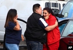 Fernando Juarez, 36, of Napa, center, embraces his 22-year-old sister Vanessa Flores, right, at the Veterans Home of California, March 9, 2018, in Yountville, Calif. Flores, who is a caregiver at the facility, exchanged texts with family while sheltering in place during a hostage situation, which ended with four people dead.