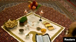 An Iranian man reads the Koran beside a traditional table 'Haft Seen' or 'Seven S', before the start of the Nowruz, or the Iranian New Year in Tehran March 20, 2009.