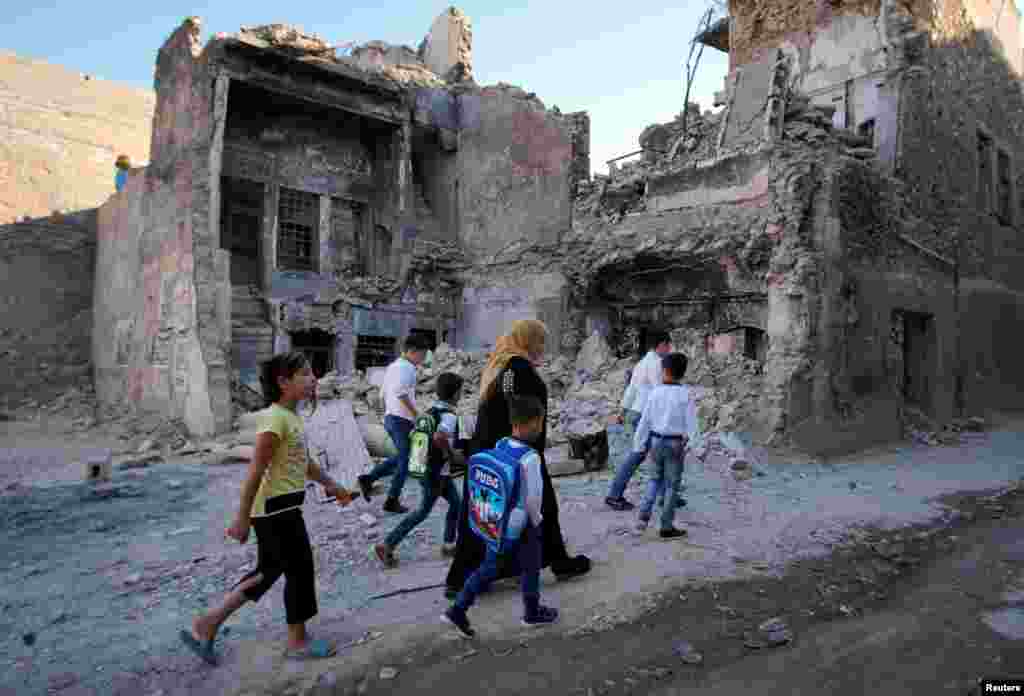 A woman walks with her kids on the first day of the new school term in the old city of Mosul, Iraq.