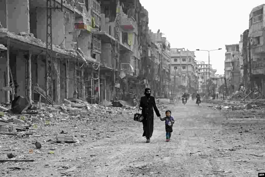 تصویری از یک زن سوری به همراه فرزندش در خیابان های ویران شده غوطه شرقی سوریه &nbsp;