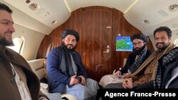 This handout photograph released by the Afghan Taliban and taken on Jan. 22, 2022 shows Taliban senior official member Anas Haqqani, right, and delegates sitting on a plane before departing to Oslo,