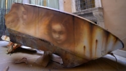 Graffitis de l'artiste de rue italien Eron sur la coque d'un bateau brisé montrant les visages d'une femme migrante et d'enfants, Rome, 14 avril 2016.
