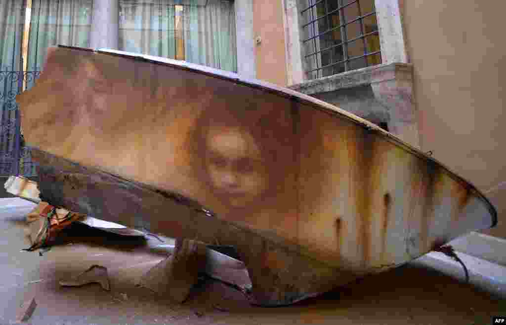 Graffiti on the side of a broken boat shows the faces of a migrant woman and children by Italian street artist Eron inside the Treccani Institute in Rome.