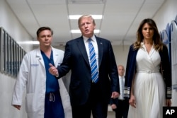 President Donald Trump, center, accompanied by first lady Melania Trump, right, and Dr. Igor Nichiporenko, left, speak to reporters while visiting with medical staff at Broward Health North in Pompano Beach, Fla., Feb. 16, 2018.