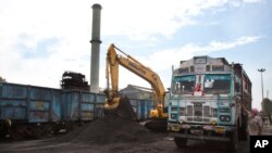 FILE- Domestically produced petroleum coke is loaded onto a truck to be transported to factories, at a railway station in Rampur, about 210 kilometers (130 miles) from New Delhi, India, July 14, 2017.