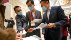 FILE - Journalists reach for copies of a Chinese government-produced report titled "Democracy That Works" at the State Council Information Office in Beijing, Dec. 4, 2021. China's Communist Party took American democracy to task that day, sharply criticizing a global democracy summit to be hosted by President Joe Biden and extolling the virtues of its governing system.