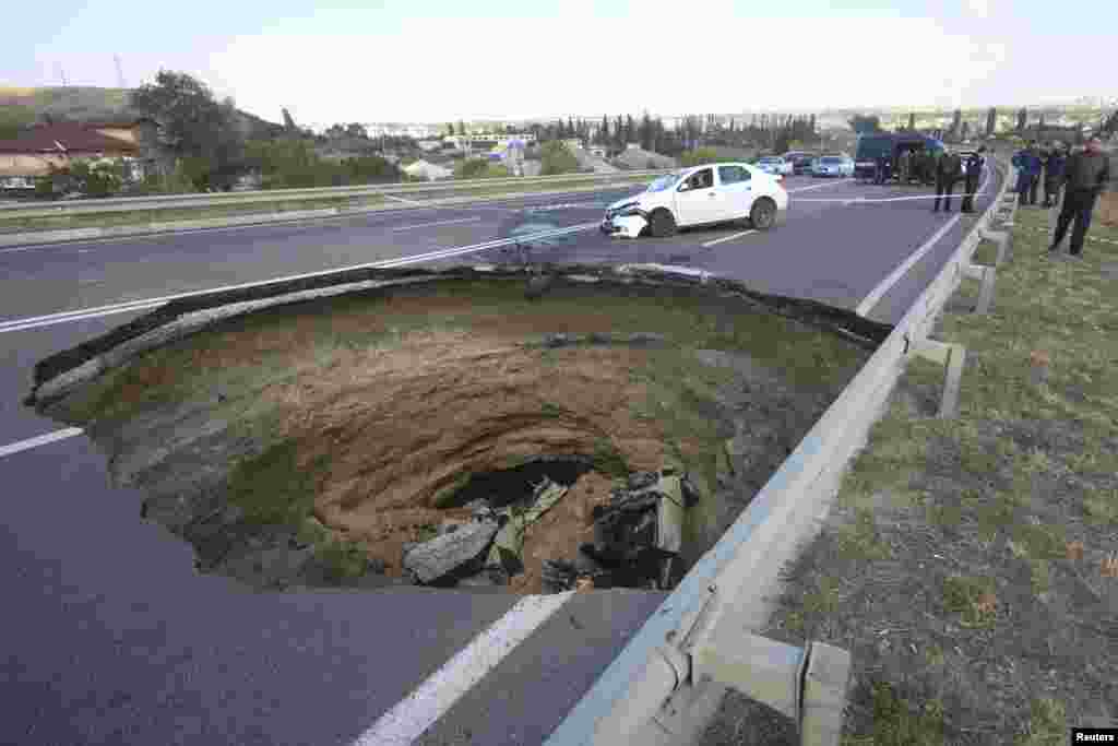 A car lies in a sinkhole in the road outside the Crimean capital Simferopol. A sinkhole about eight meters wide and deep opened up on the road between Nikolayev and Yevpatoria highway, killing six people tavelling in a car which fell into the pit, according to local media. 