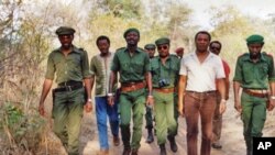 Jardo Muekalia (primeiro à esquerda), com João Vahekeny, Brigadeiro Mango, Rito Chitekulu, Tenente-Coronel Virgilio "Dick" Fortado, Oscar Sakala, Honório Van Dunen, e Paulo Lukamba Gato fotografados no interior de Angola