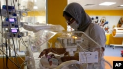 FILE: A Moroccan nurse takes care of one of the nine babies protected in an incubator at the maternity ward of the private clinic of Ain Borja in Casablanca, Morocco, Wednesday, May 5, 2021. 