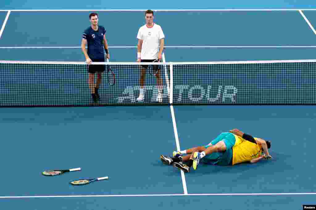 Australia's Alex de Minaur and Nick Kyrgios celebrate winning their Quarter Final doubles match against Britain's Jamie Murray and Joe Salisbury as they look on dejected at the ATP Cup in Sydney, Australia.